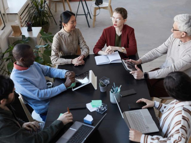 Diverse Team of People in Business Meeting Above View Top view at large diverse group of business people sitting at table during briefing meeting in office